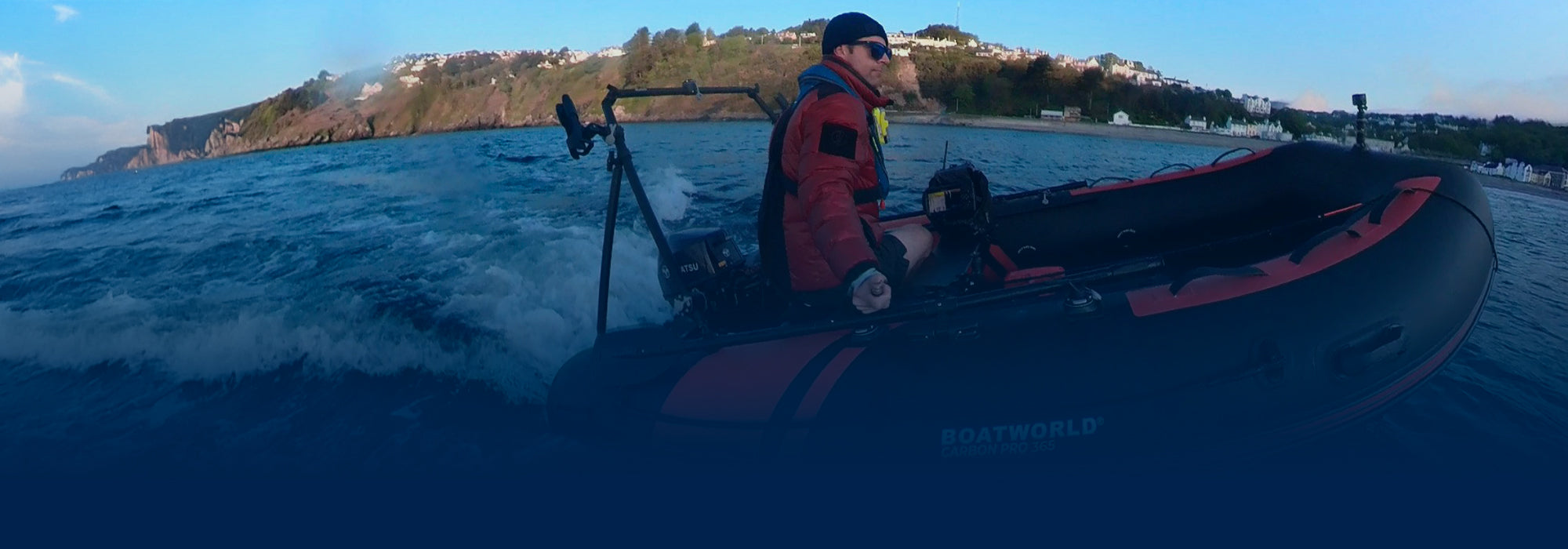Matt from Airborne Pirates rides the Boatworld Carbon Pro 365 small inflatable boat across choppy waters, with Borkia accessories fitted and a rugged coastline in the background.
